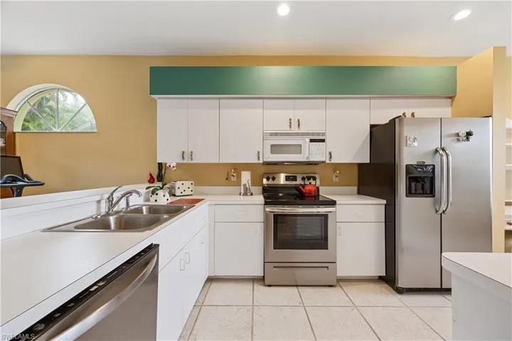 Kitchen featuring white cabinetry, stainless steel appliances, a double basin sink, white countertops, and tiled flooring