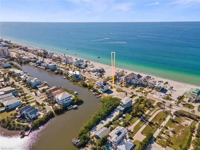 Aerial view of property and surrounding area featuring expansive coastline and nearby suburban area