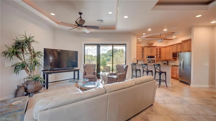 Living room with a tray ceiling, a ceiling fan, and recessed lighting