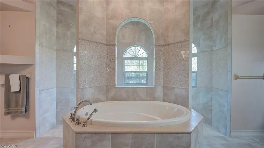 Primary full bath with a bath, a walk in shower, and tile walls