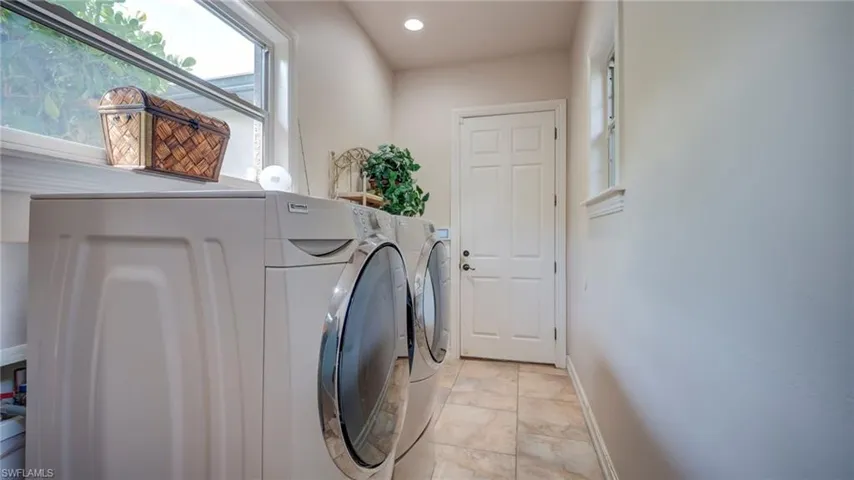 Laundry area featuring washing machine and dryer and recessed lighting leading to the garage