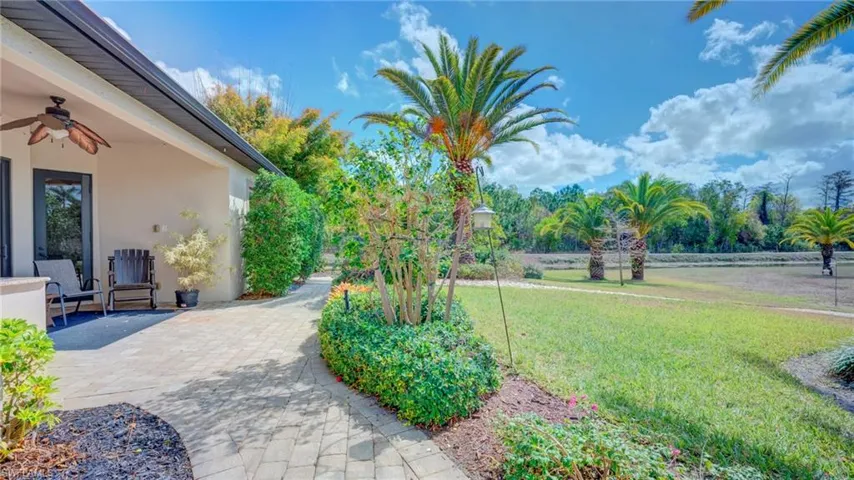 View of grassy yard featuring a ceiling fan and a patio