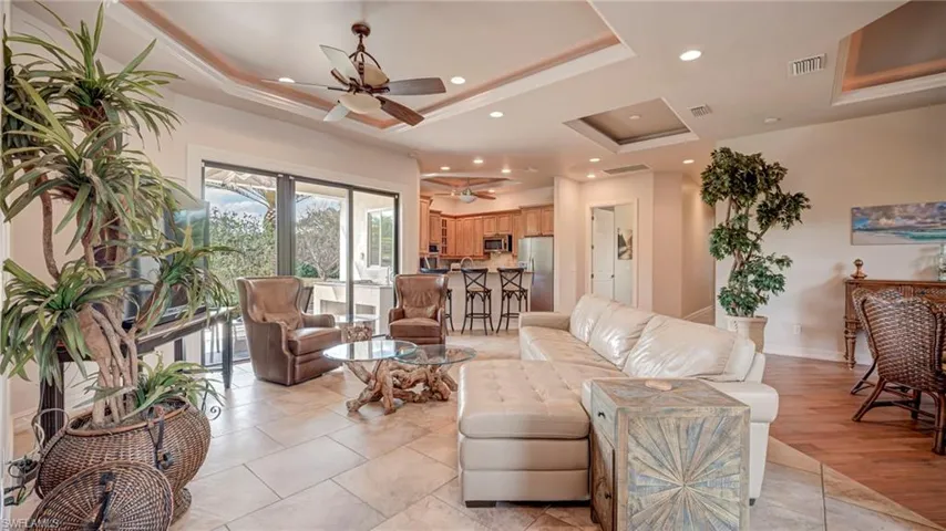 Living area with a tray ceiling, a ceiling fan, and recessed lighting