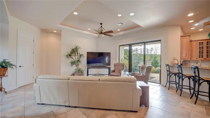 Living room with a raised ceiling, ceiling fan, and recessed lighting