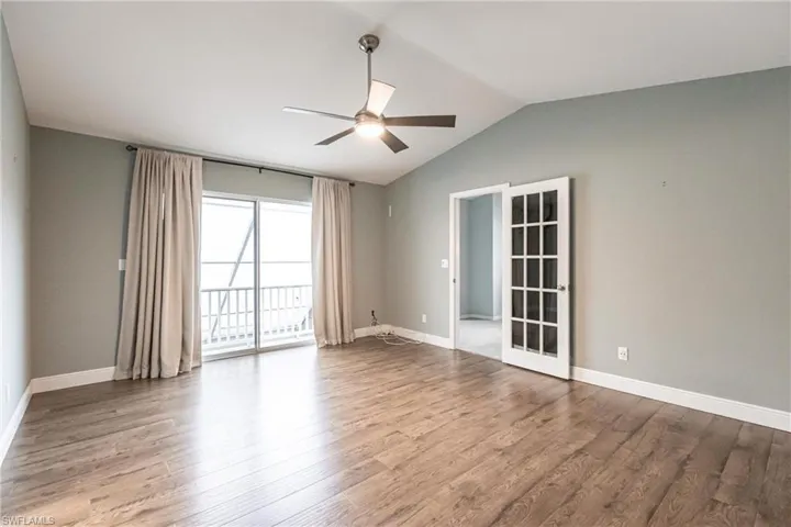 Empty room featuring light wood-type flooring, ceiling fan, and lofted ceiling