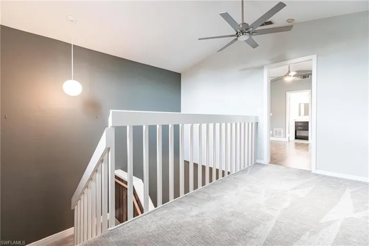 Hallway featuring light carpet and vaulted ceiling