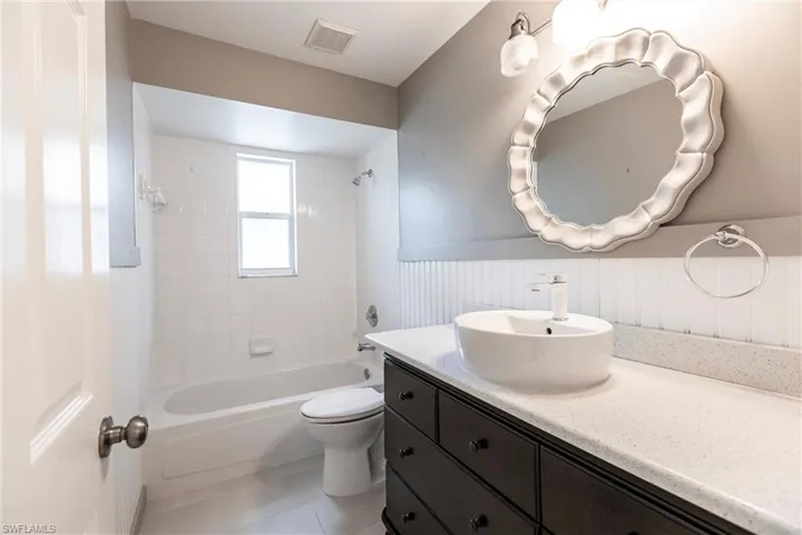 Full bathroom featuring vanity, tiled shower / bath combo, toilet, and tile patterned flooring