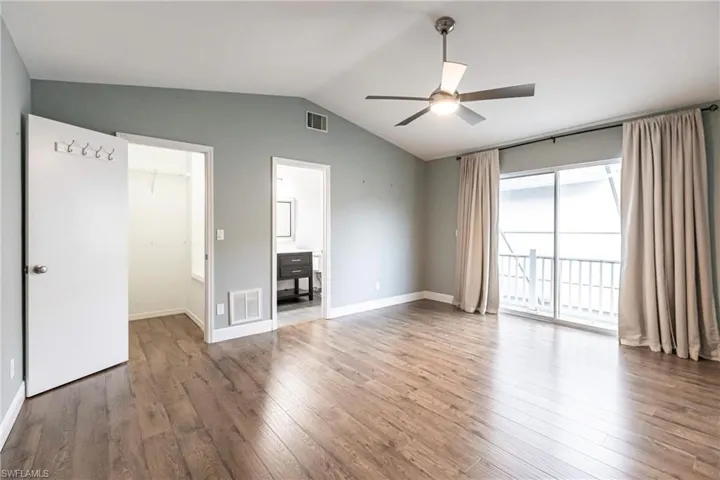 Unfurnished bedroom with a walk in closet, access to outside, ceiling fan, wood-type flooring, and a closet