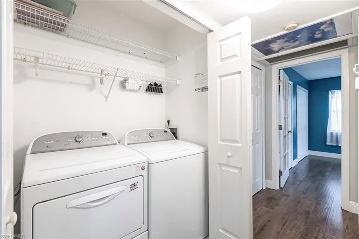 Laundry room with dark hardwood / wood-style flooring and washing machine and clothes dryer