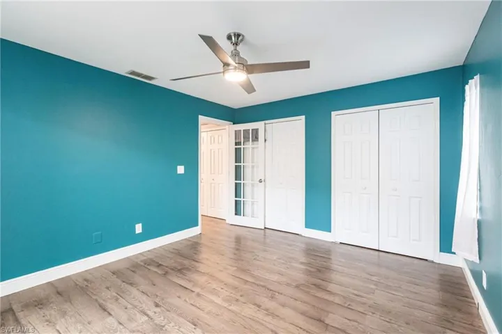 Unfurnished bedroom featuring ceiling fan, light hardwood / wood-style floors, and two closets