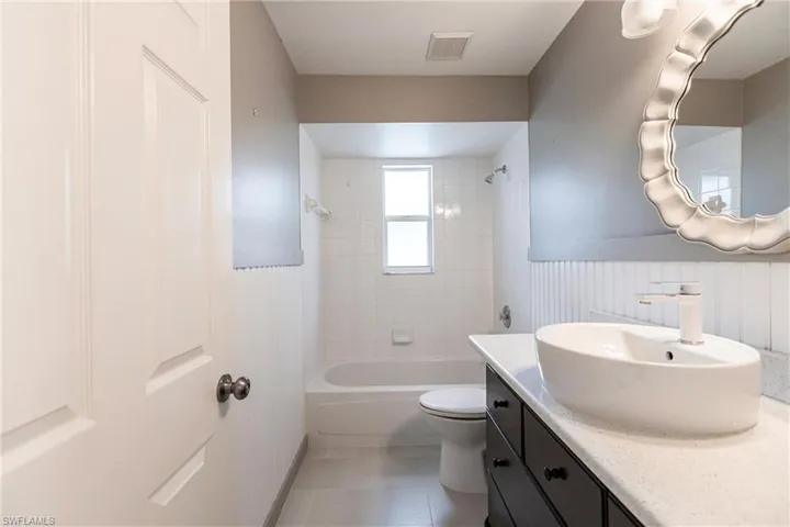 Full bathroom with tile patterned flooring, vanity, tiled shower / bath combo, and toilet