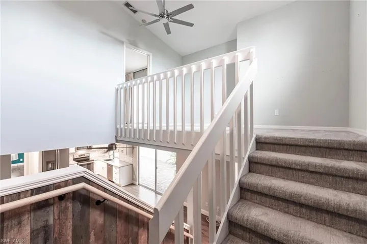 Stairway with wood-type flooring and vaulted ceiling