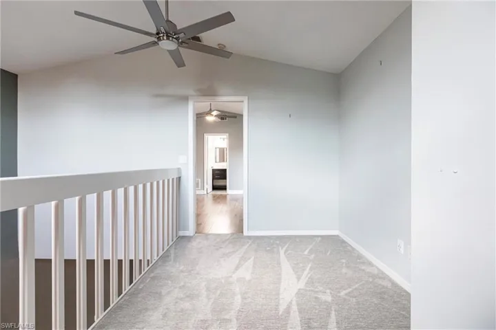 Hall with carpet flooring and lofted ceiling