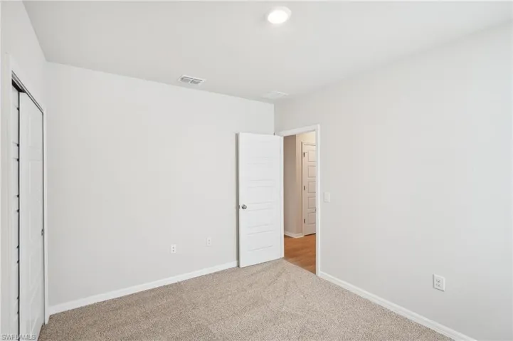 Unfurnished bedroom with light carpet and a closet