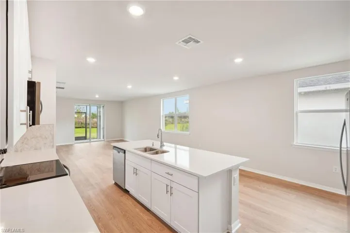 Kitchen featuring a center island with sink, light wood-type flooring, sink, white cabinets, and dishwasher