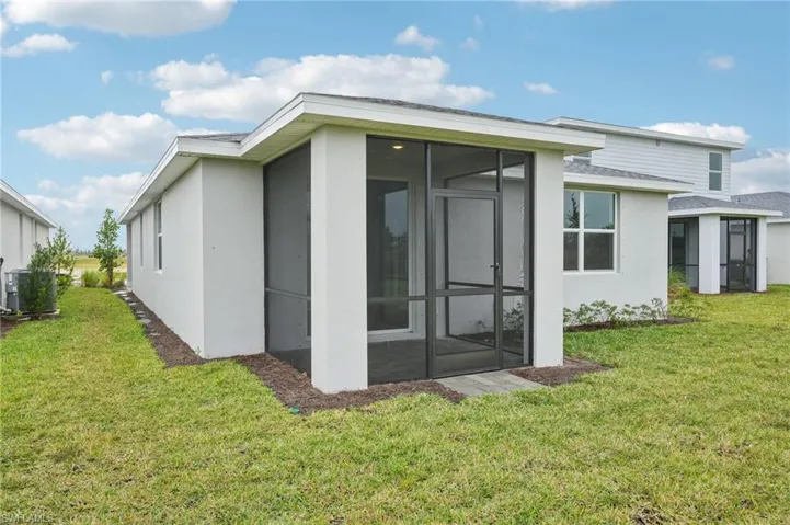Rear view of property with a sunroom, a yard, and cooling unit