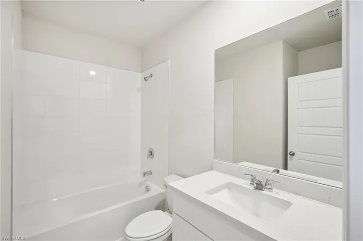 Full bathroom featuring toilet, tiled shower / bath combo, and vanity