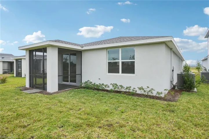Rear view of house featuring a lawn, central AC, and a sunroom