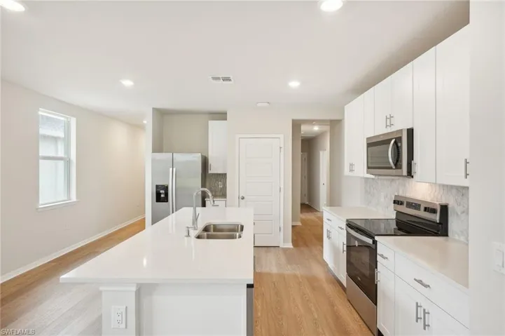 Kitchen featuring stainless steel appliances, light hardwood / wood-style floors, white cabinetry, and sink