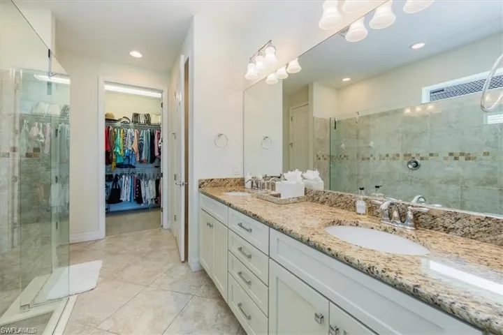 Full bath with a shower stall, double vanity, a walk in closet, light tile patterned floors, and recessed lighting