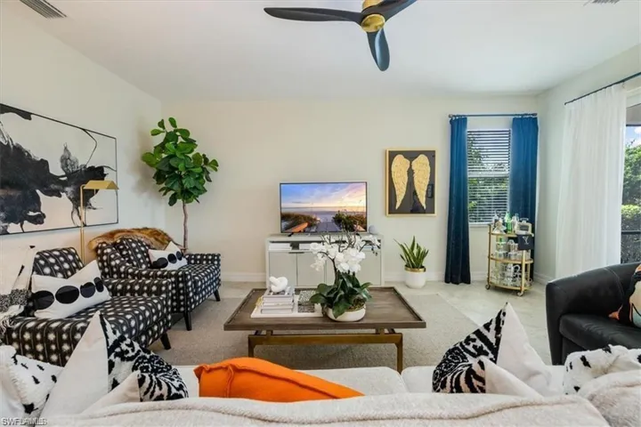 Tiled living room featuring ceiling fan and baseboards