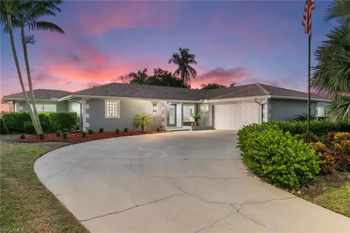Ranch-style house featuring stucco siding, an attached garage, a tile roof, and driveway