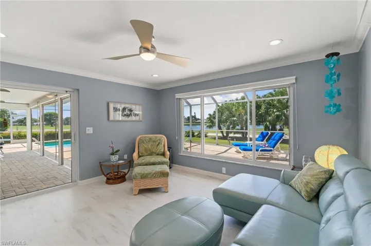 Living area with wood finished floors, baseboards, a ceiling fan, and ornamental molding