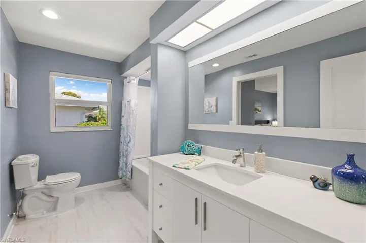 Full bath with toilet, shower / tub combo with curtain, recessed lighting, baseboards, and vanity