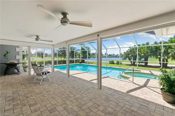 View of swimming pool with glass enclosure, a pool with connected hot tub, a patio, and ceiling fan