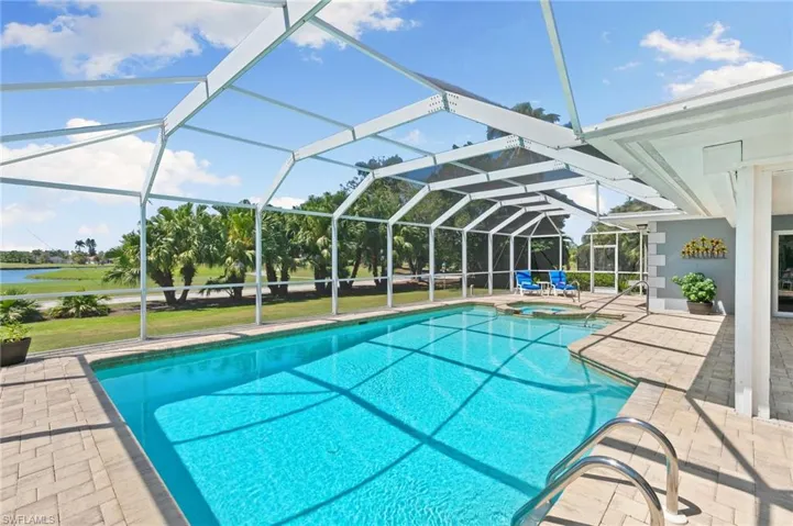 View of pool featuring glass enclosure, a pool with connected hot tub, and a patio area