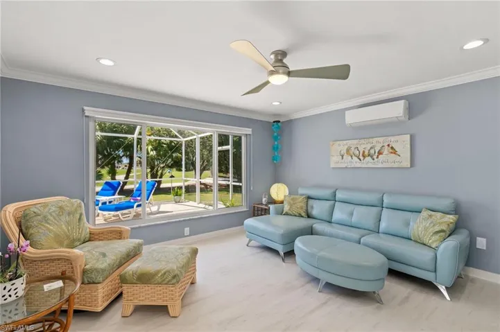 Living area featuring wood finished floors, baseboards, ceiling fan, an AC wall unit, and crown molding