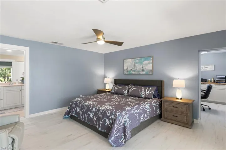 Bedroom featuring light wood finished floors, visible vents, connected bathroom, baseboards, and a ceiling fan