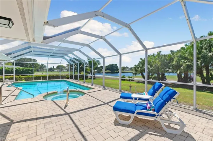 View of pool with a lanai, a patio area, a water view, and a pool with connected hot tub
