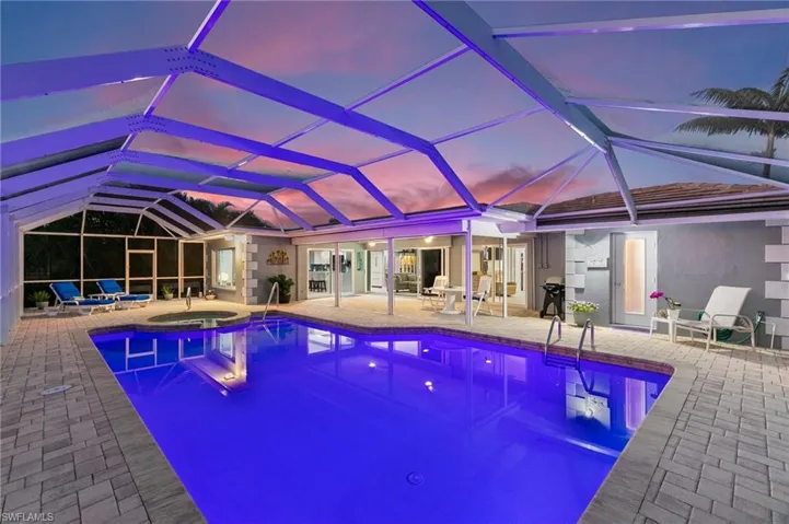 View of swimming pool with a lanai, grilling area, a pool with connected hot tub, and a patio