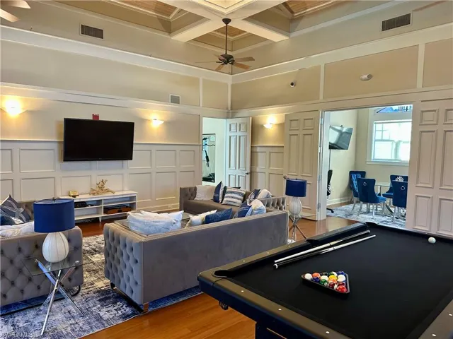 Recreation room with a decorative wall, pool table, a ceiling fan, coffered ceiling, and wood finished floors