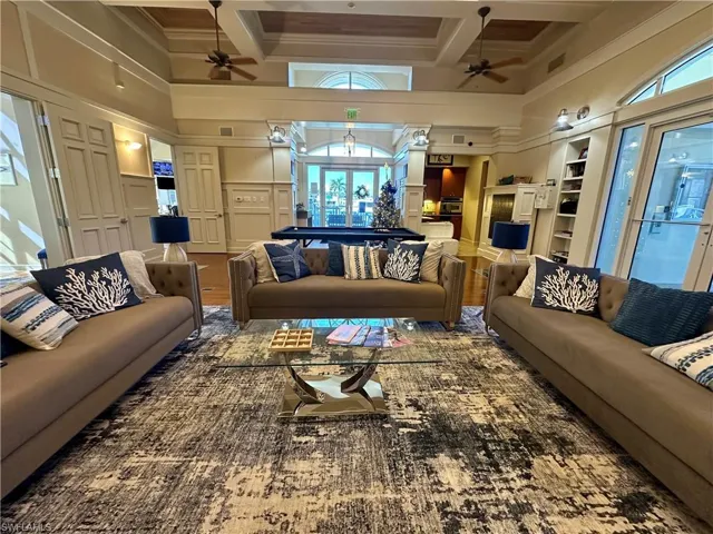 Living area featuring a high ceiling, a decorative wall, coffered ceiling, and wood finished floors