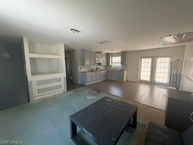 Open-concept room featuring built-in shelving, a full kitchen, and double glass-paneled doors