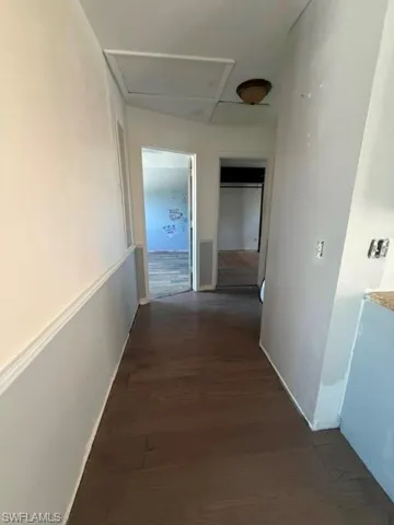 Hardwood-finish flooring extending through a hallway with wainscoting and baseboards