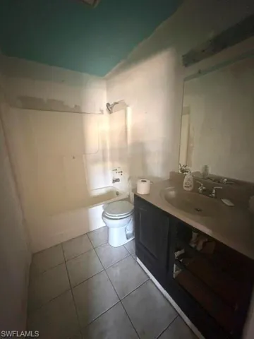 Bathroom featuring a shower/tub combination, floor tiles, and a vanity with an integrated sink