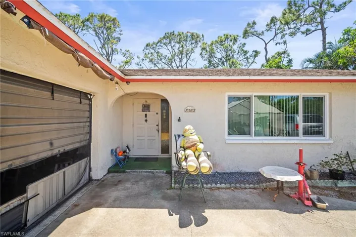 Property entrance featuring stucco siding, a patio area, and roof with shingles