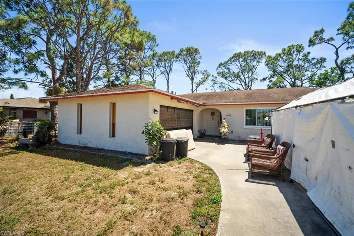 Back of house with driveway, stucco siding, a patio, a lawn, and a garage
