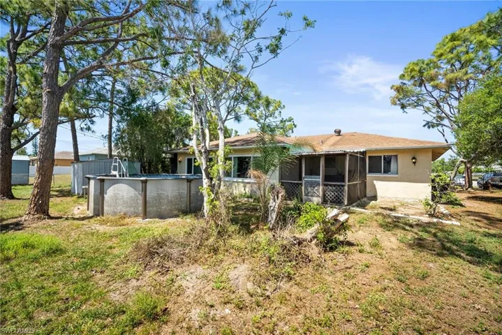 Back of property with stucco siding, a sunroom, and an outdoor pool