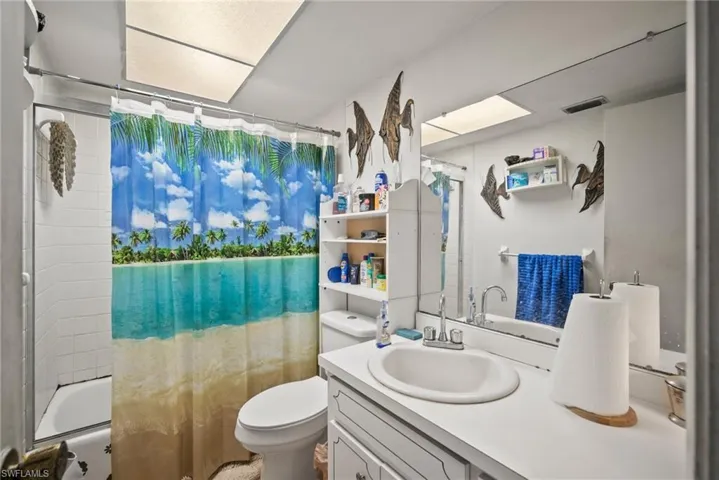 Bathroom featuring shower / bath combination with curtain, toilet, vanity, and visible vents