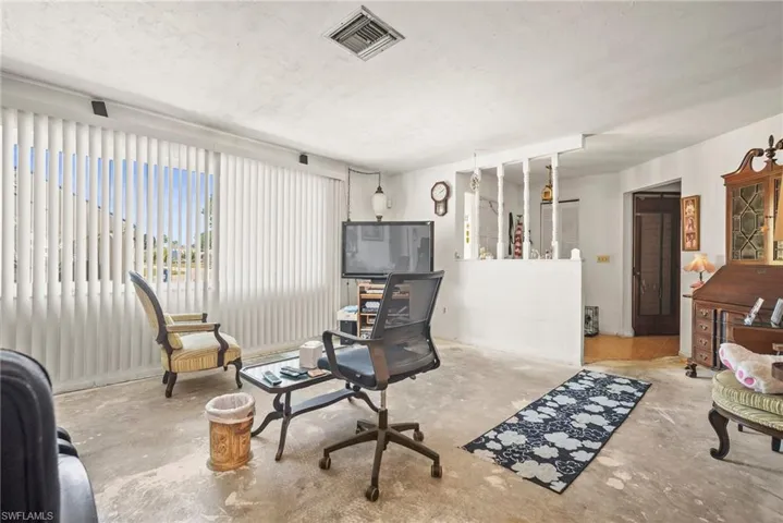 Living area featuring visible vents, unfinished concrete floors, and a textured ceiling