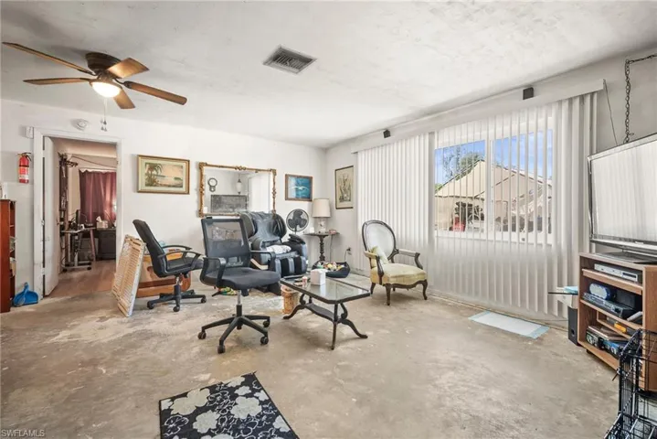 Home office featuring a textured ceiling, visible vents, concrete flooring, and a ceiling fan