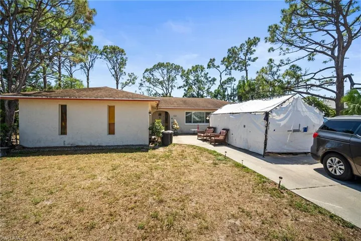 Rear view of house featuring a lawn, stucco siding, and a patio area
