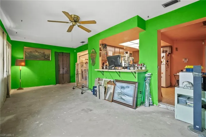 Misc room with unfinished concrete flooring, visible vents, and a ceiling fan