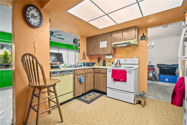 Kitchen with light countertops, white appliances, brown cabinets, a ceiling fan, and under cabinet range hood