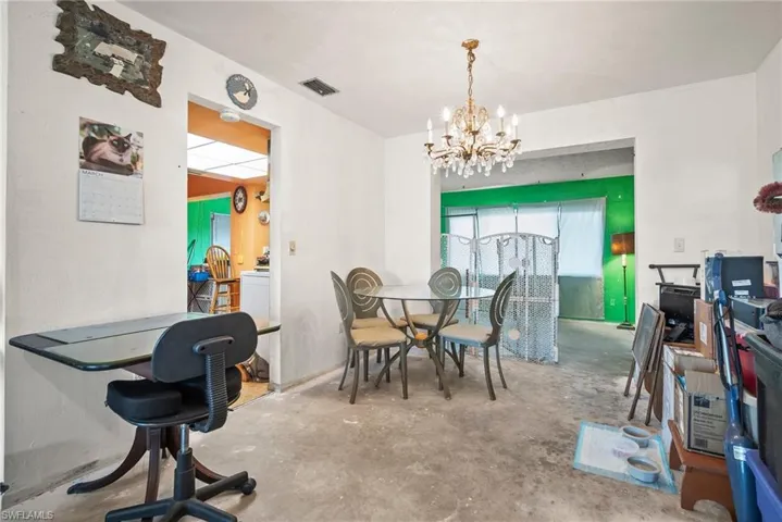 Dining room featuring concrete flooring, a notable chandelier, and visible vents