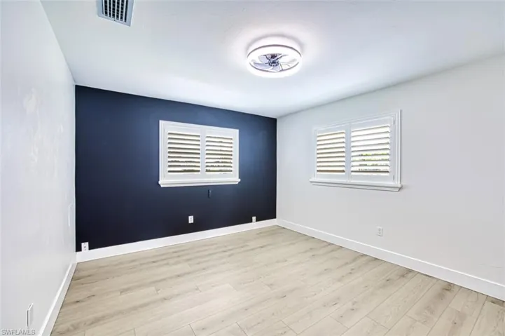 Empty room featuring wood finished floors, visible vents, and baseboards